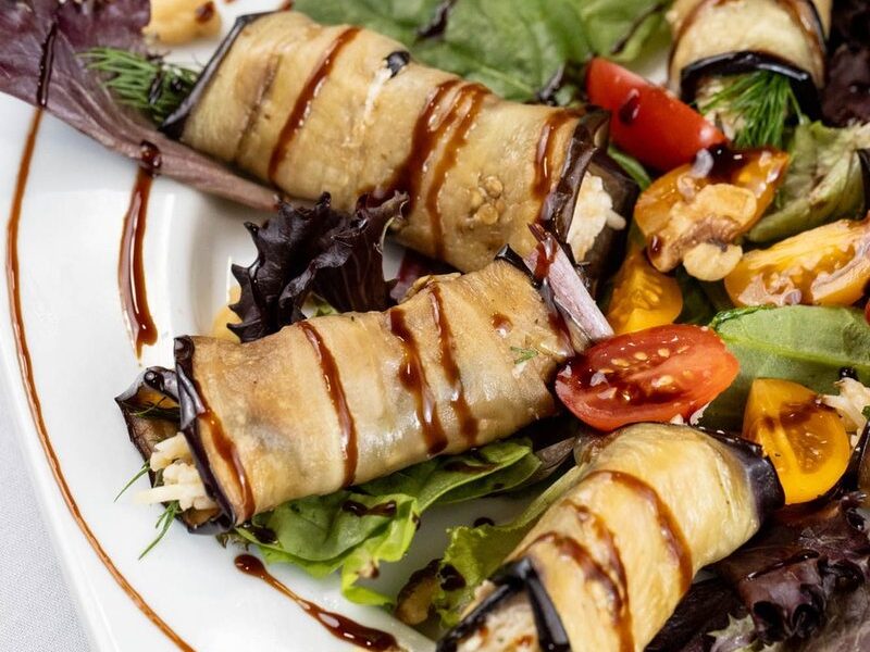 Eggplant rolls drizzled with balsamic glaze on fresh greens
