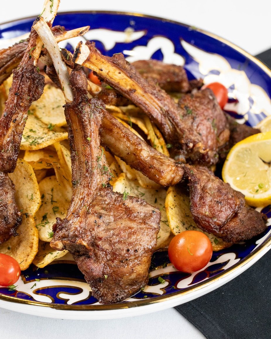 Lamb chops with crispy potatoes and lemon on a blue Uzbek plate